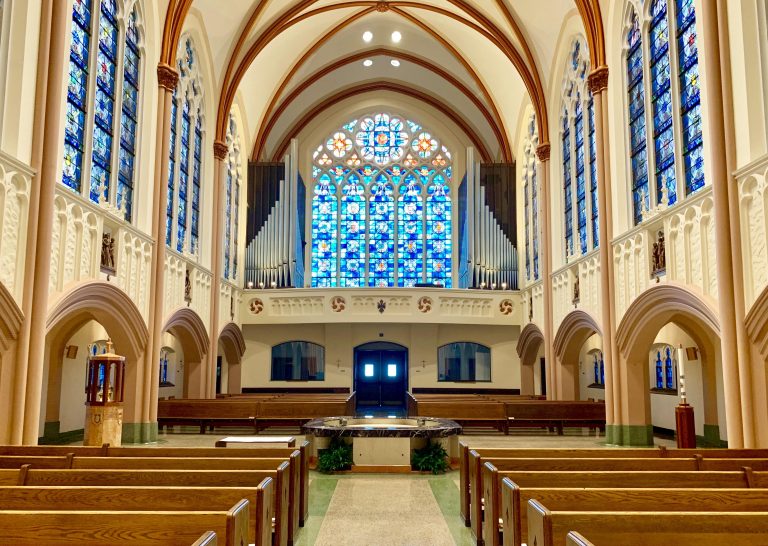 The back of the cathedral showing a large blue stained glass window and the pipe organ.