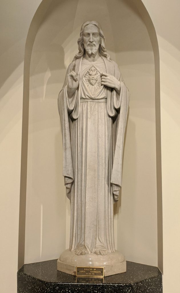 A stone statue of Jesus pointing to his Sacred Heart.