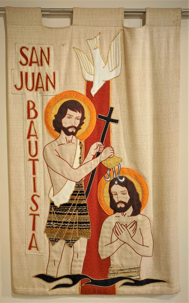 A fabric image of Jesus being baptized by Saint  John the Baptist with the Holy Spirit coming down in the form of a dove.